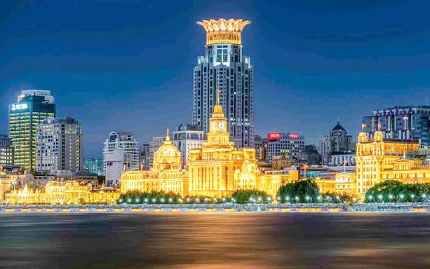 Night view of the illuminated Bund skyline along the Huangpu River in Shanghai, China.