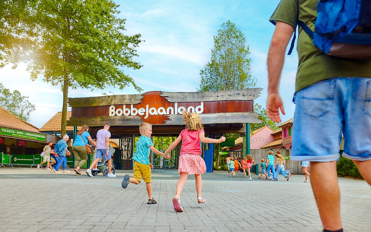 Children running towards Bobbejaanland theme park entrance.