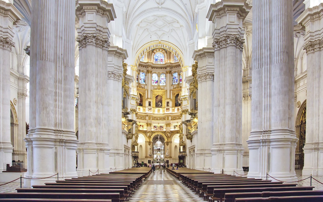 Granada Cathedral interior with ornate columns and stained glass windows.