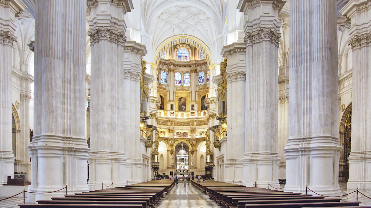 Granada Cathedral interior with ornate columns and stained glass windows.