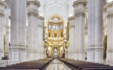 Granada Cathedral interior with ornate columns and stained glass windows.