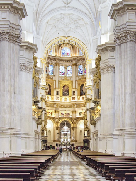 Granada Cathedral interior with ornate columns and stained glass windows.
