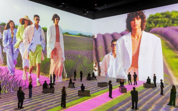 Fashion show projection with models walking on a lavender field runway at Vogue: Inventing the Runway event.