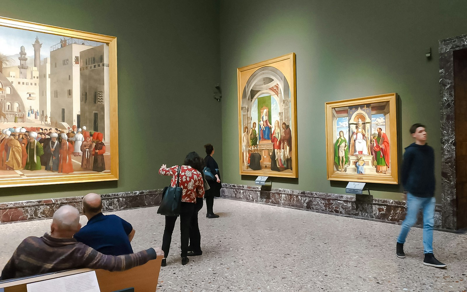 Visitors admire paintings in the Pinacoteca di Brera museum in Milan, surrounded by art and historical ambiance.