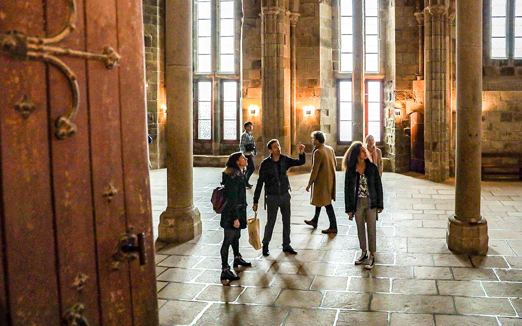 Visitors with a guide exploring the interior of Mont Saint-Michel Abbey.