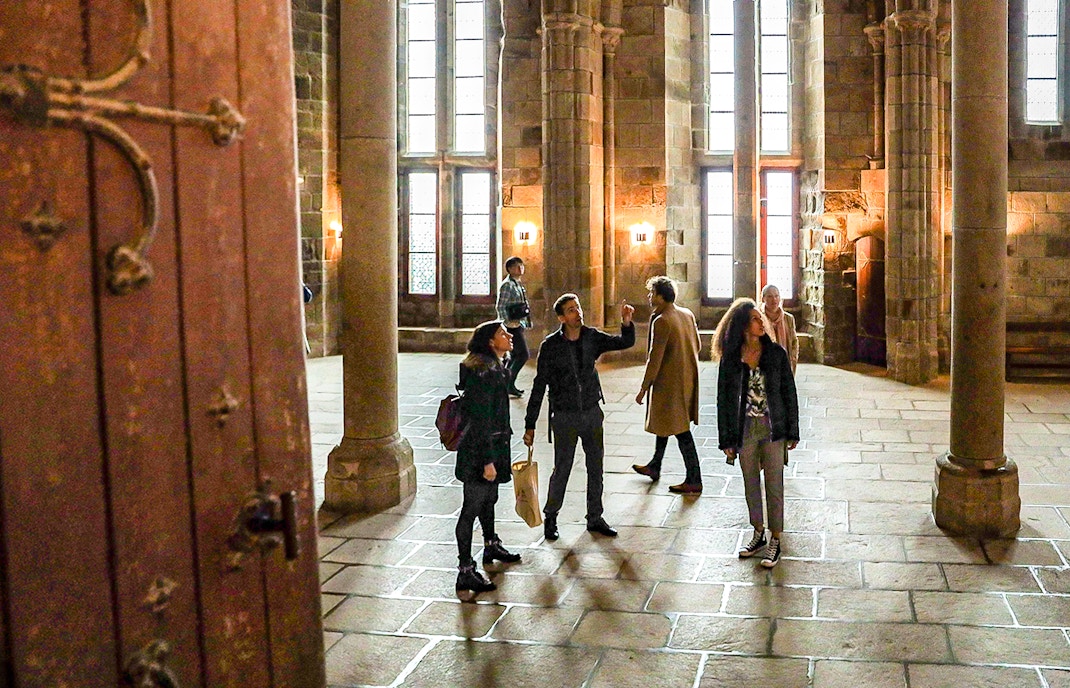 Mont Saint Michel abbey with tourists exploring the historic island on a guided tour, Normandy, France.