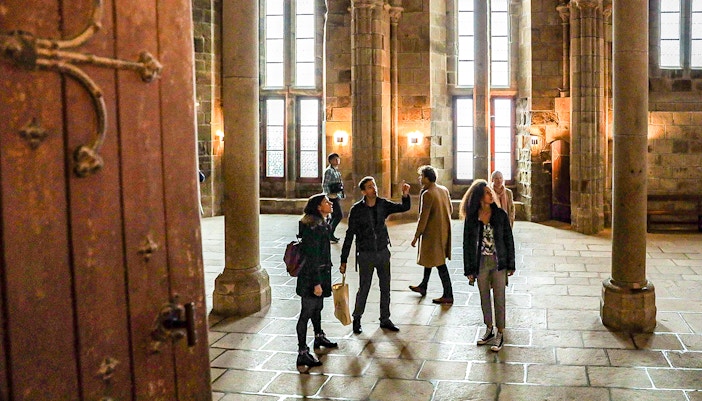 Mont Saint Michel abbey with tourists exploring the historic island on a guided tour, Normandy, France.