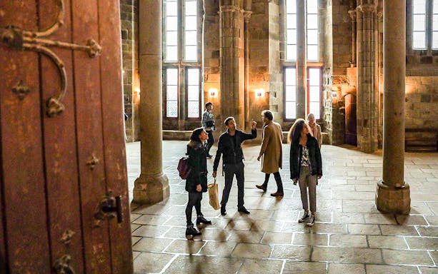 Visitors with a guide exploring the interior of Mont Saint-Michel Abbey.