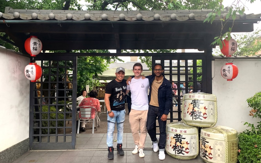 Visitors at a Kyoto sake brewery entrance with traditional lanterns and sake barrels.