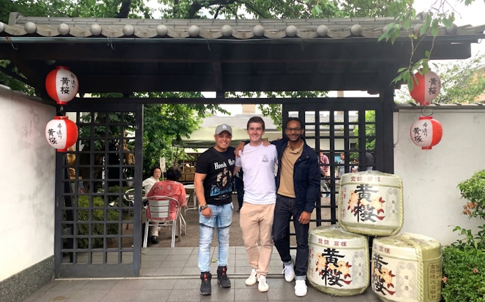 Visitors at a Kyoto sake brewery entrance with traditional lanterns and sake barrels.