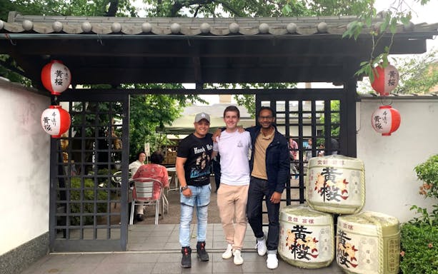 Visitors at a Kyoto sake brewery entrance with traditional lanterns and sake barrels.