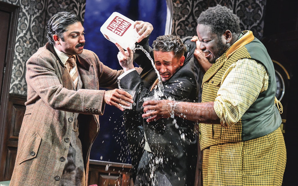Actors in a comedic scene from "The Play That Goes Wrong" with water being poured.