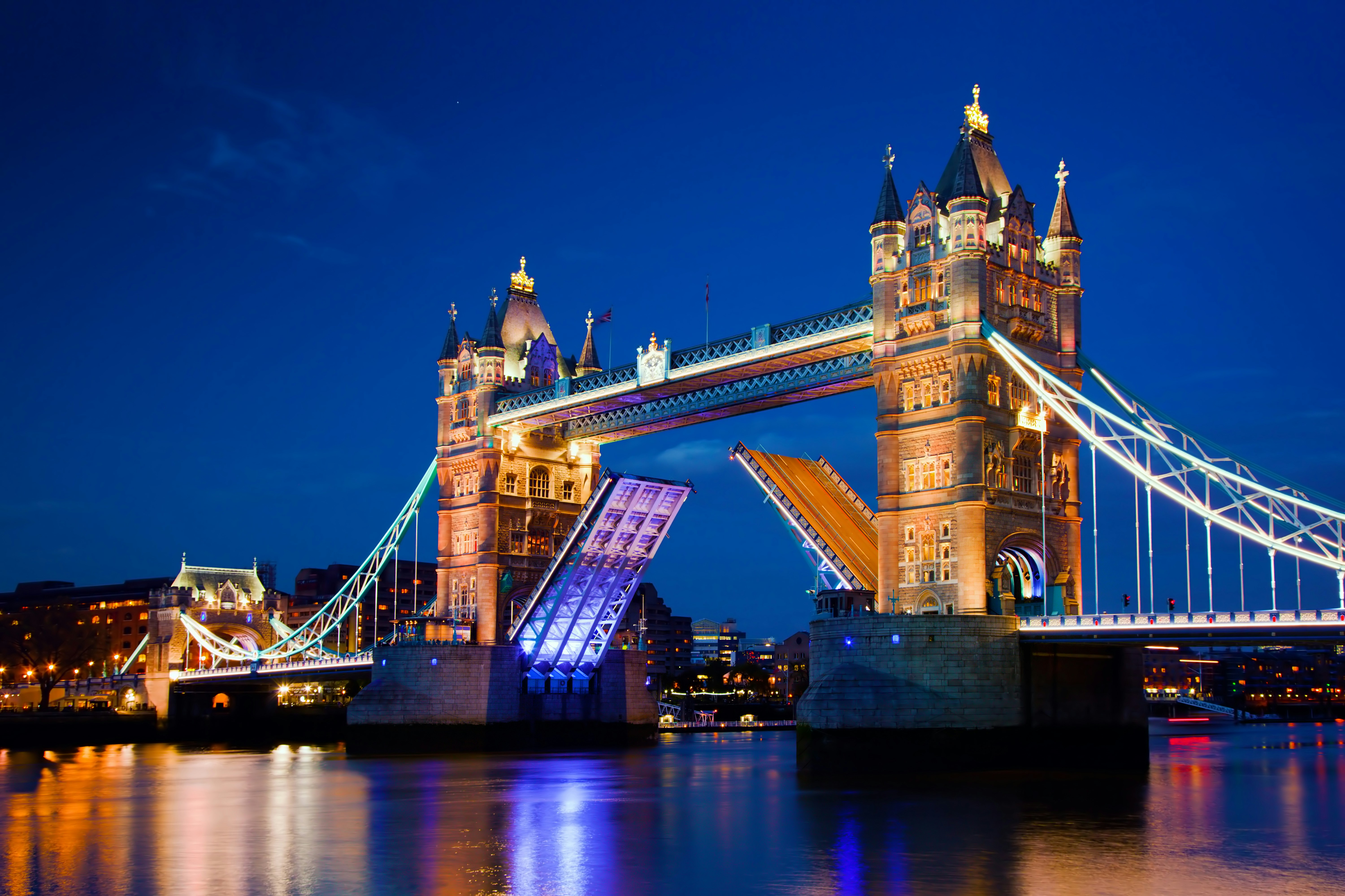 Tower Bridge in London illuminated at night with raised bascules.