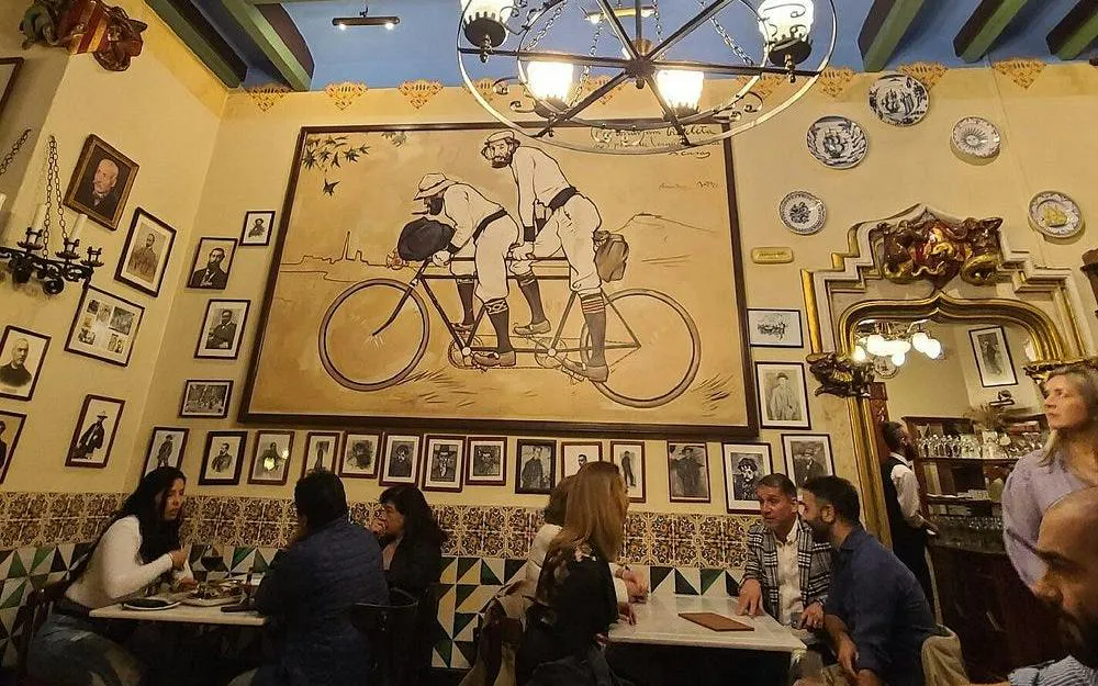 Dining area at Els Quatre Gats in Barcelona, featuring modernist artwork and patrons enjoying a meal.
