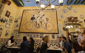 Dining area at Els Quatre Gats in Barcelona, featuring modernist artwork and patrons enjoying a meal.