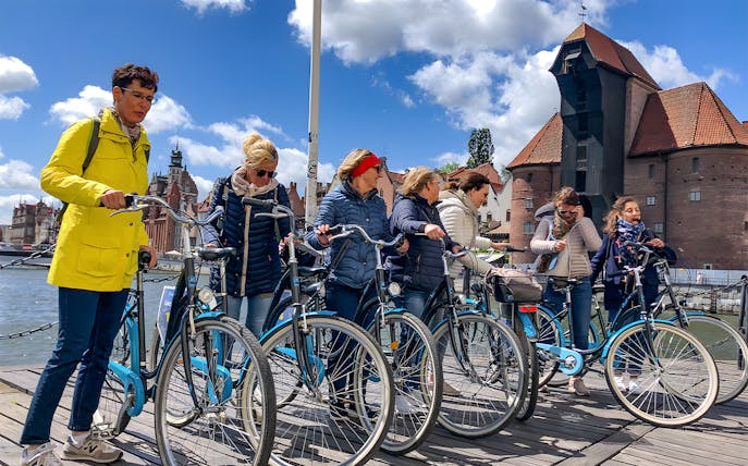 Group of cyclists on a Gdansk bike tour near historic waterfront buildings.