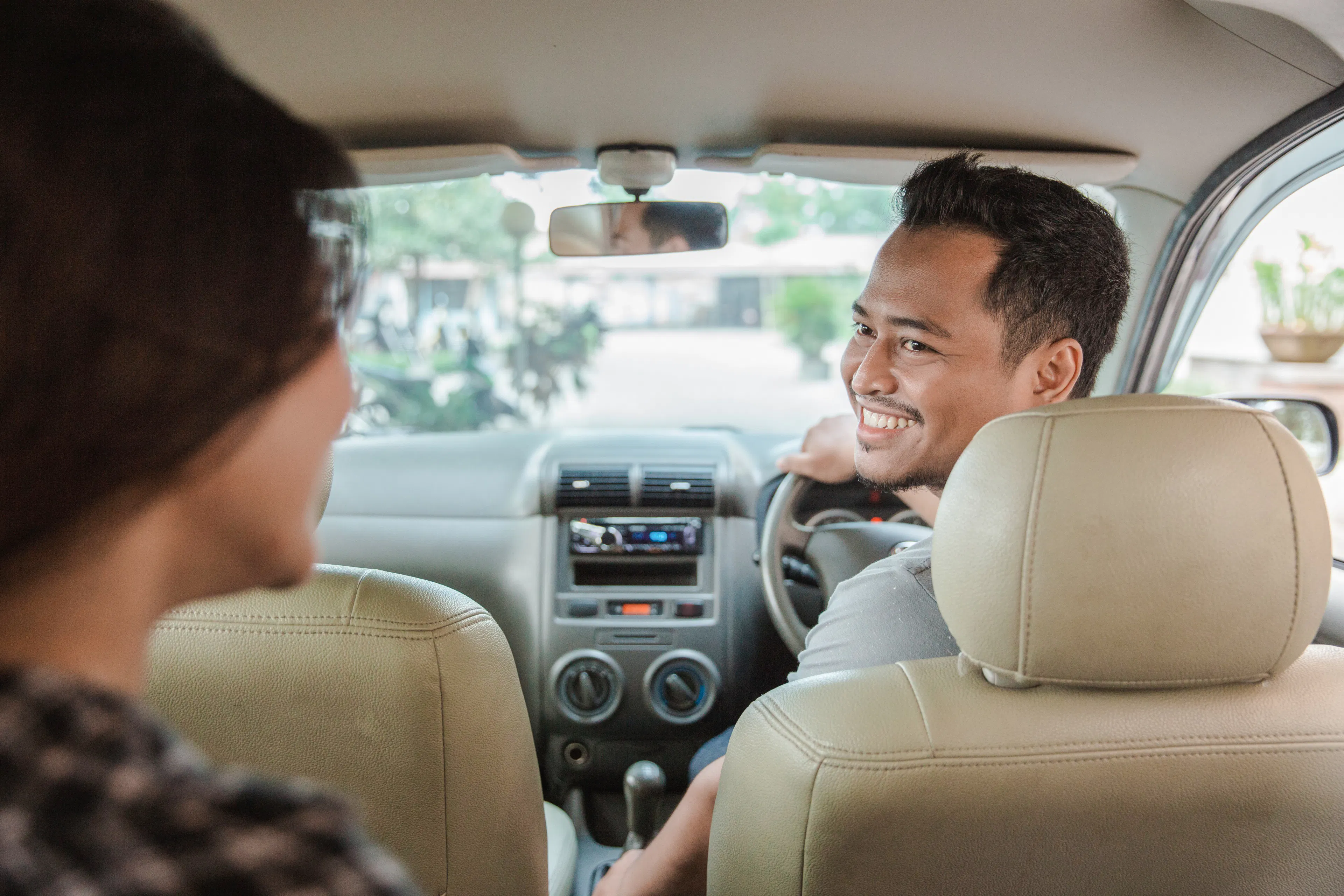Driver smiling at passenger in a private car during Bali full-day charter.