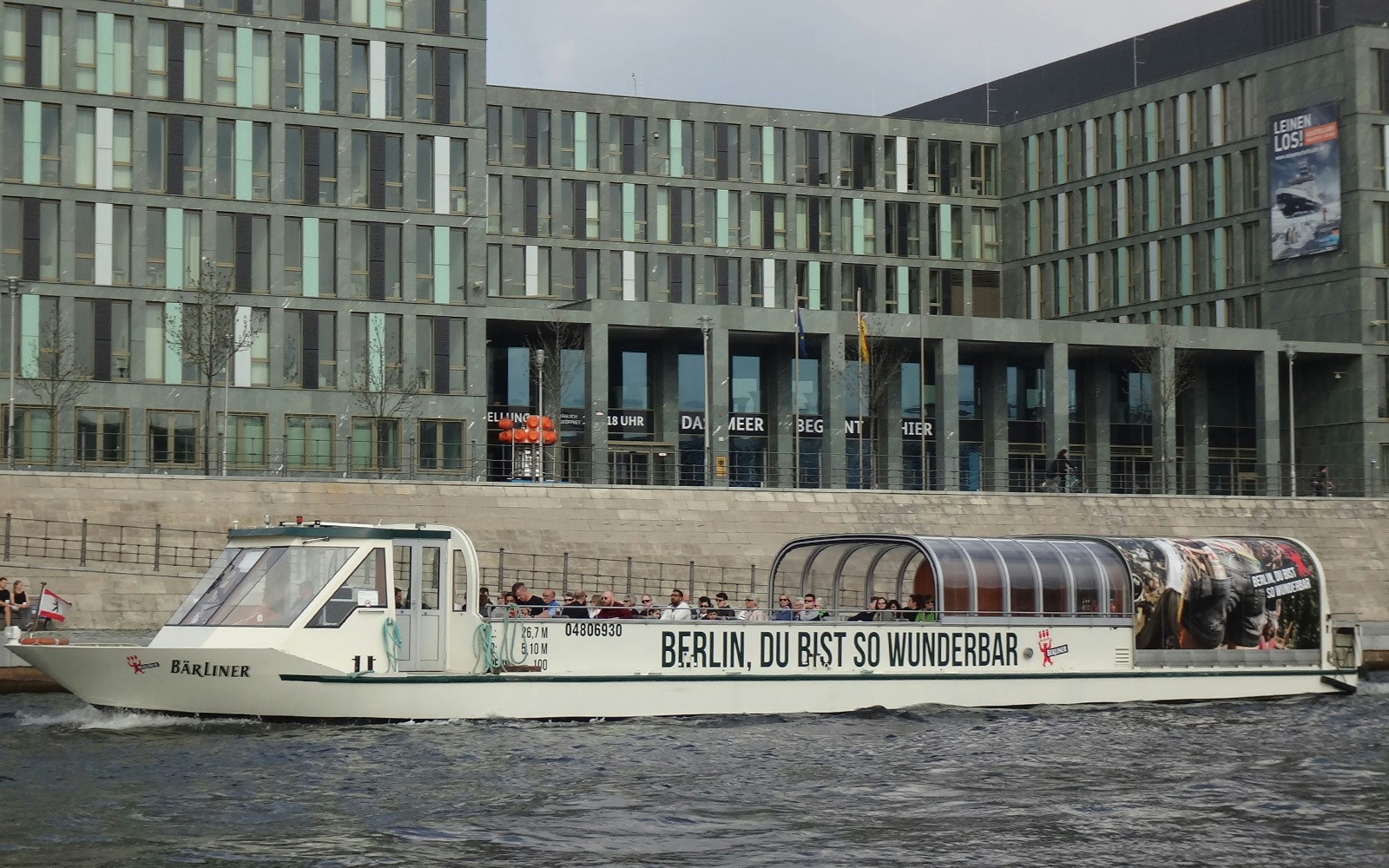 Sightseeing cruise boat on the River Spree in Berlin passing modern buildings.