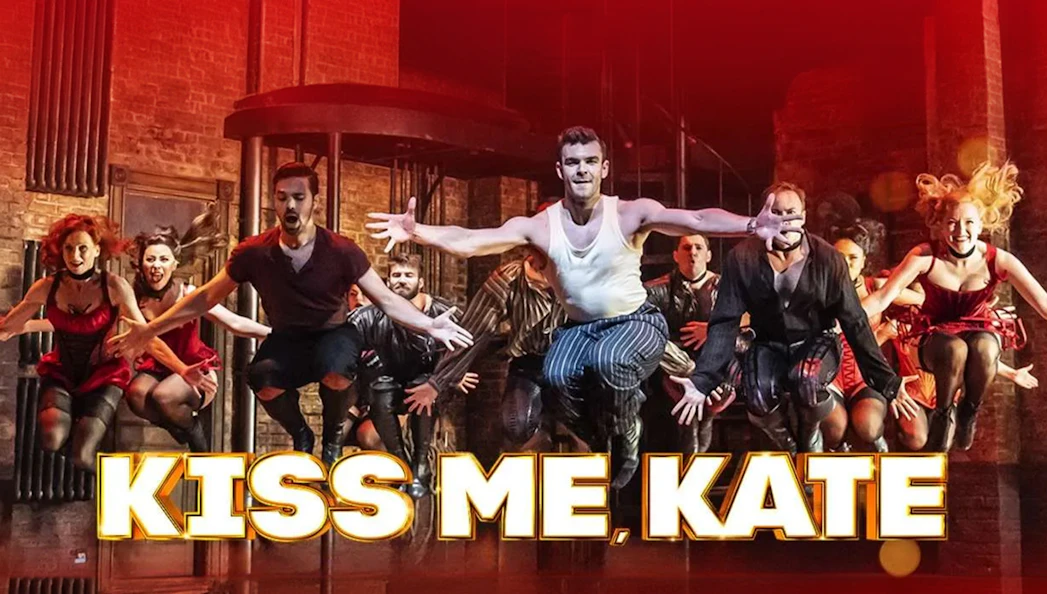 Performers dancing energetically on stage in "Kiss Me, Kate" musical.
