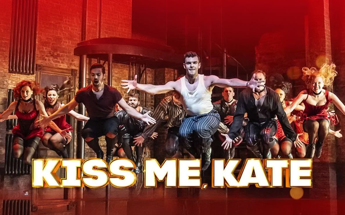 Performers dancing energetically on stage in "Kiss Me, Kate" musical.