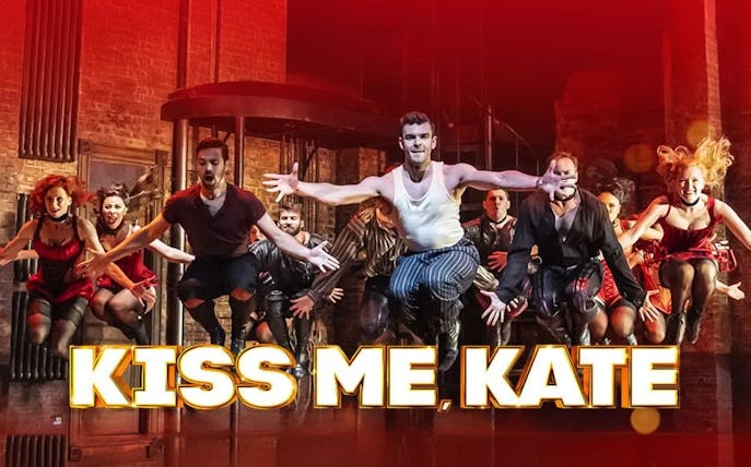 Performers dancing energetically on stage in "Kiss Me, Kate" musical.