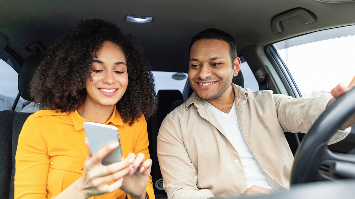 Couple using smartphone for navigation during car travel.