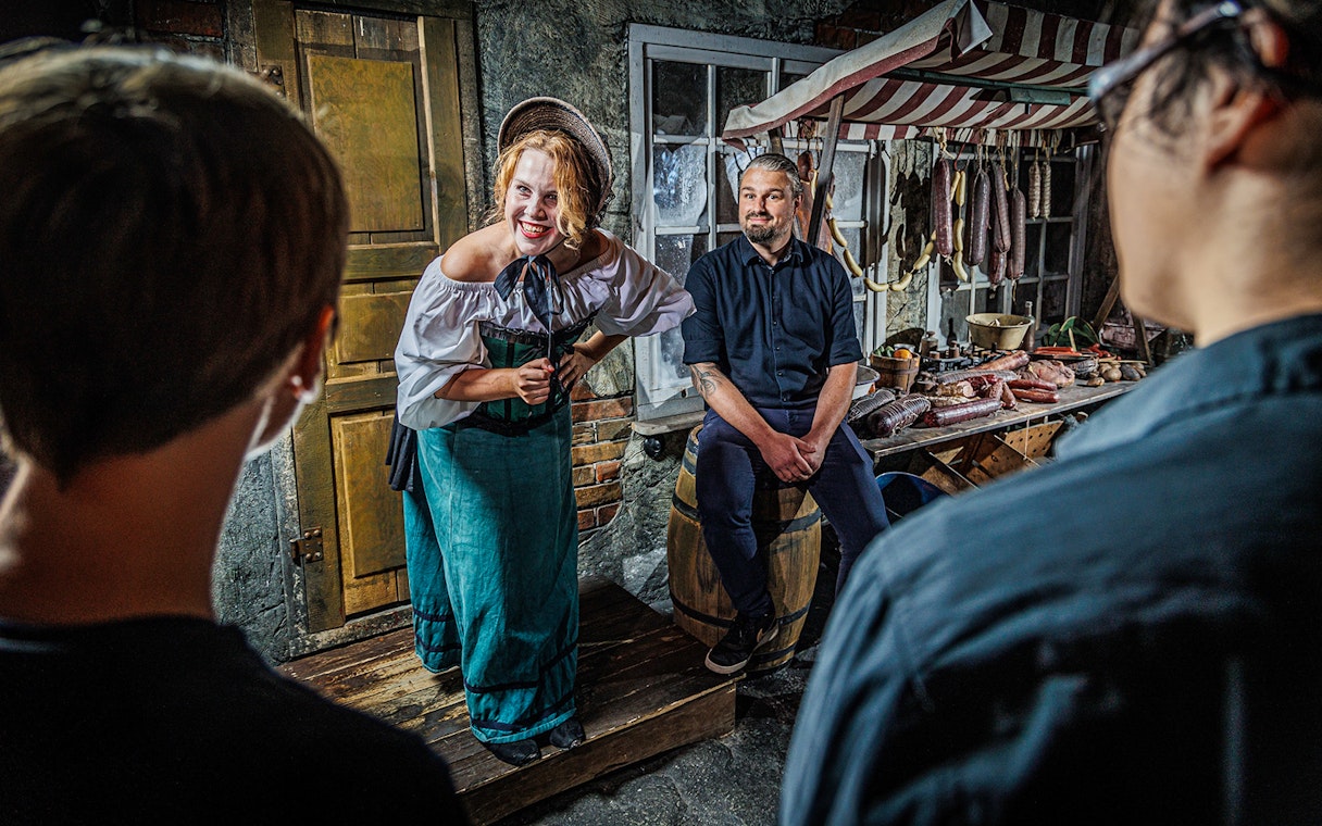 Tour guide in historical costume engaging visitors inside Berlin Dungeon.