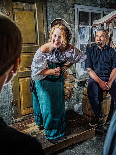 Tour guide in historical costume engaging visitors inside Berlin Dungeon.