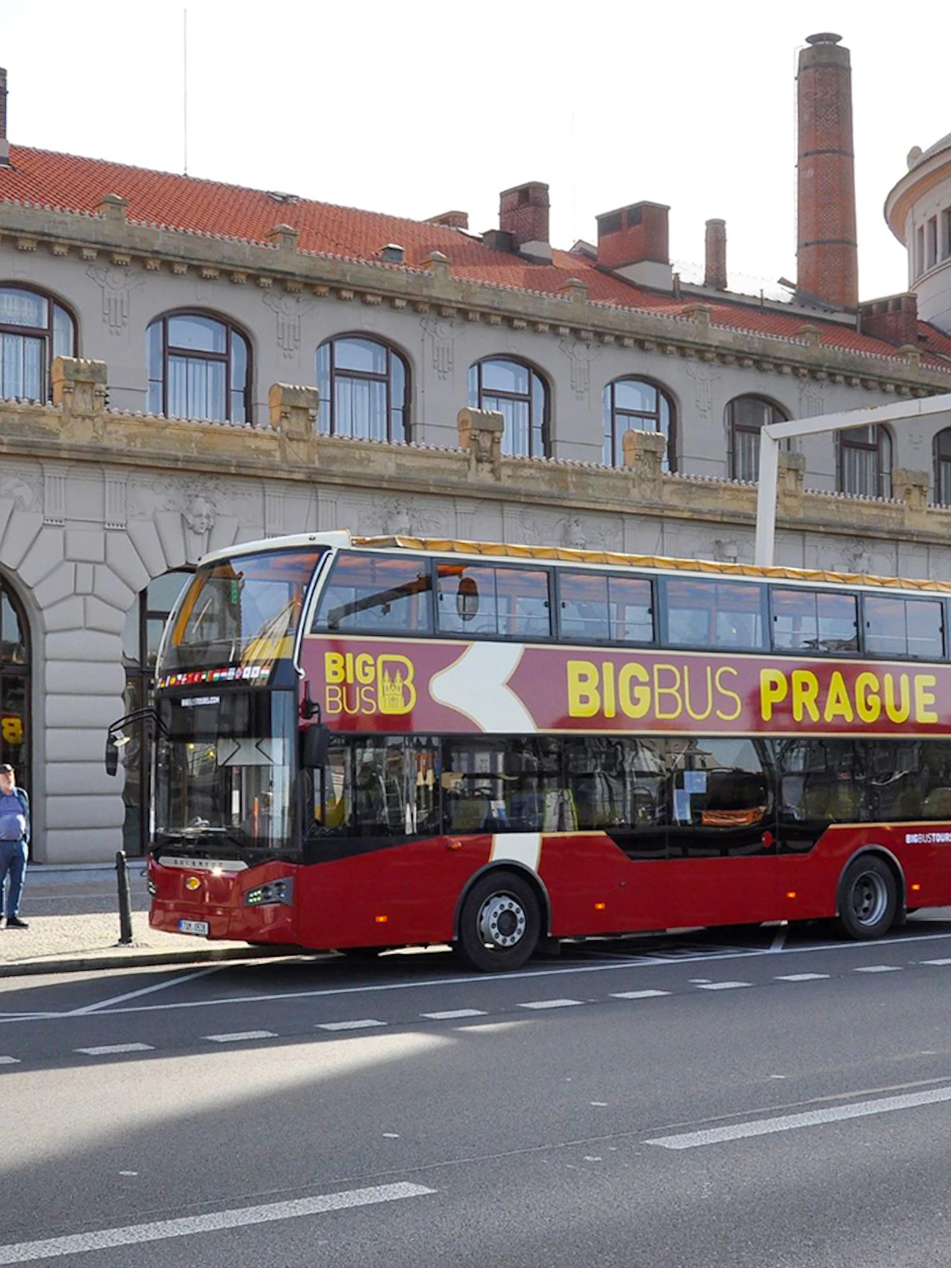 Hop on hop off bus in front of historic building in Prague.