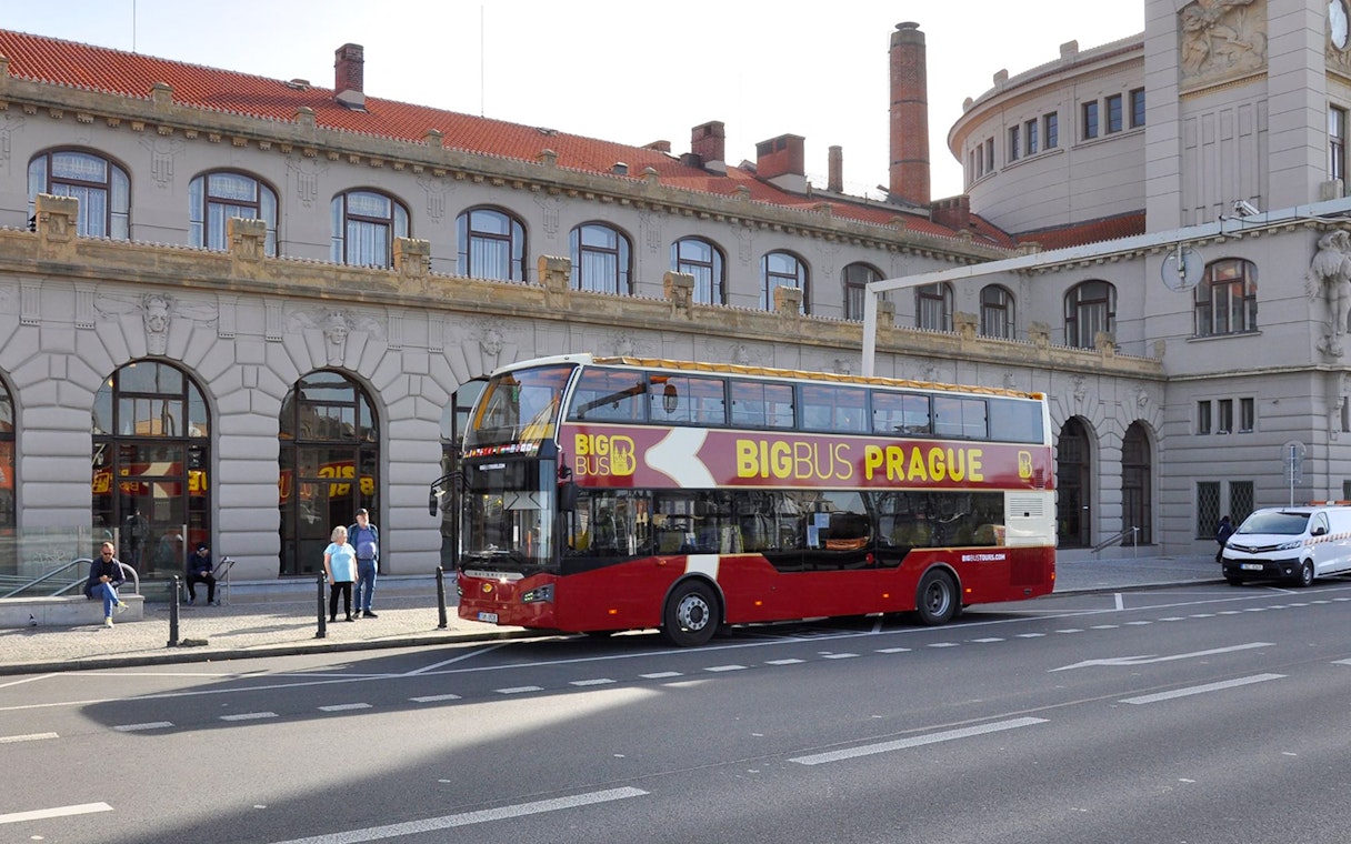 Hop on hop off bus in front of historic building in Prague.