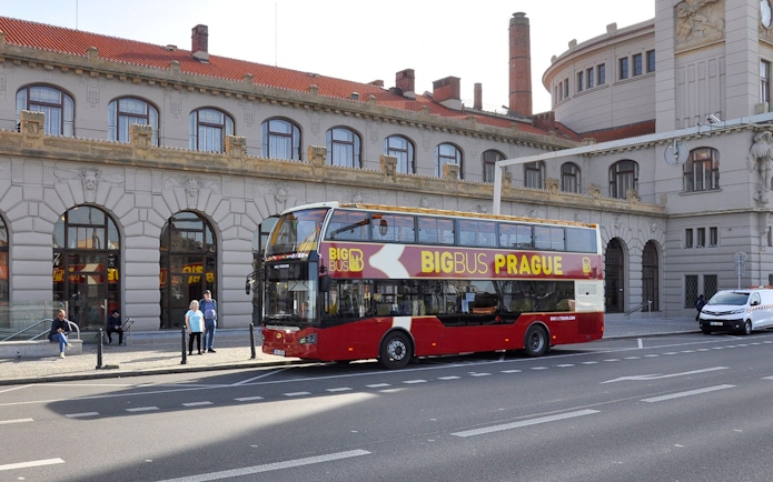 Hop on hop off bus in front of historic building in Prague.