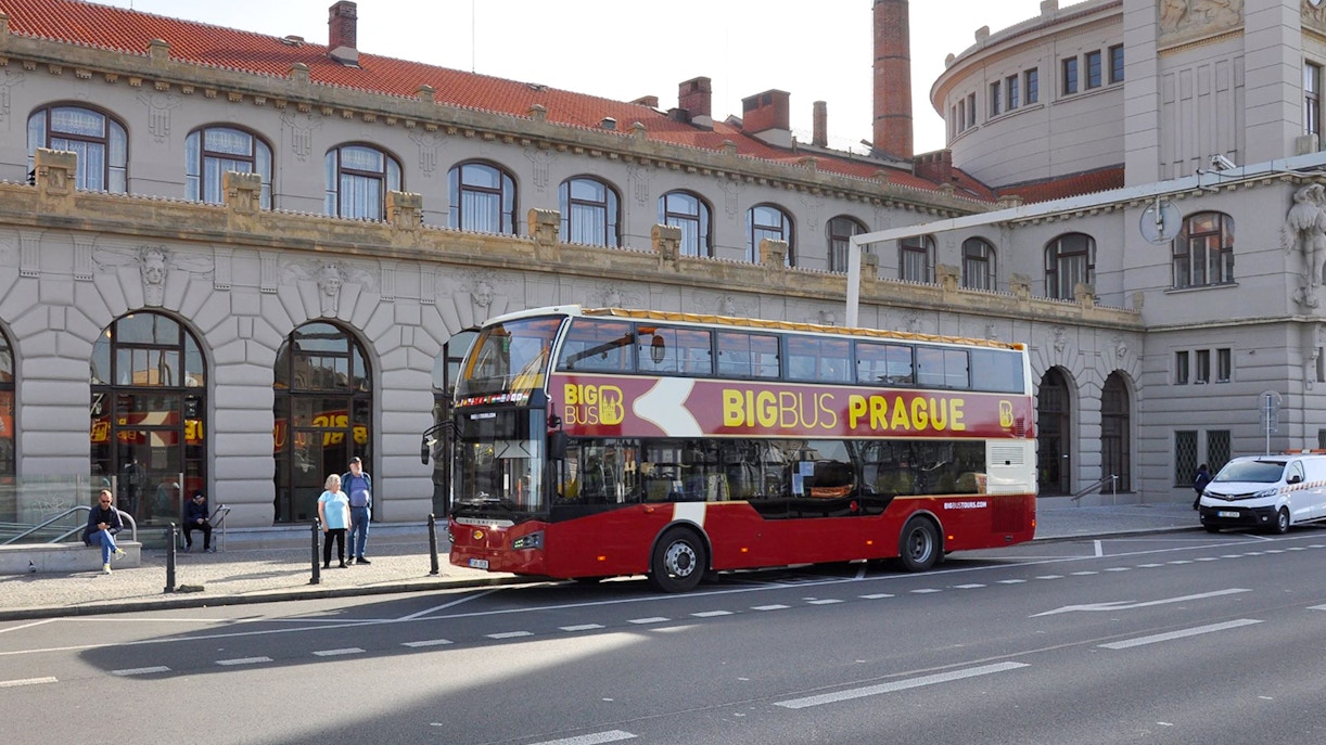 Prague hop-on hop-off bus near Charles Bridge with tourists exploring city landmarks.