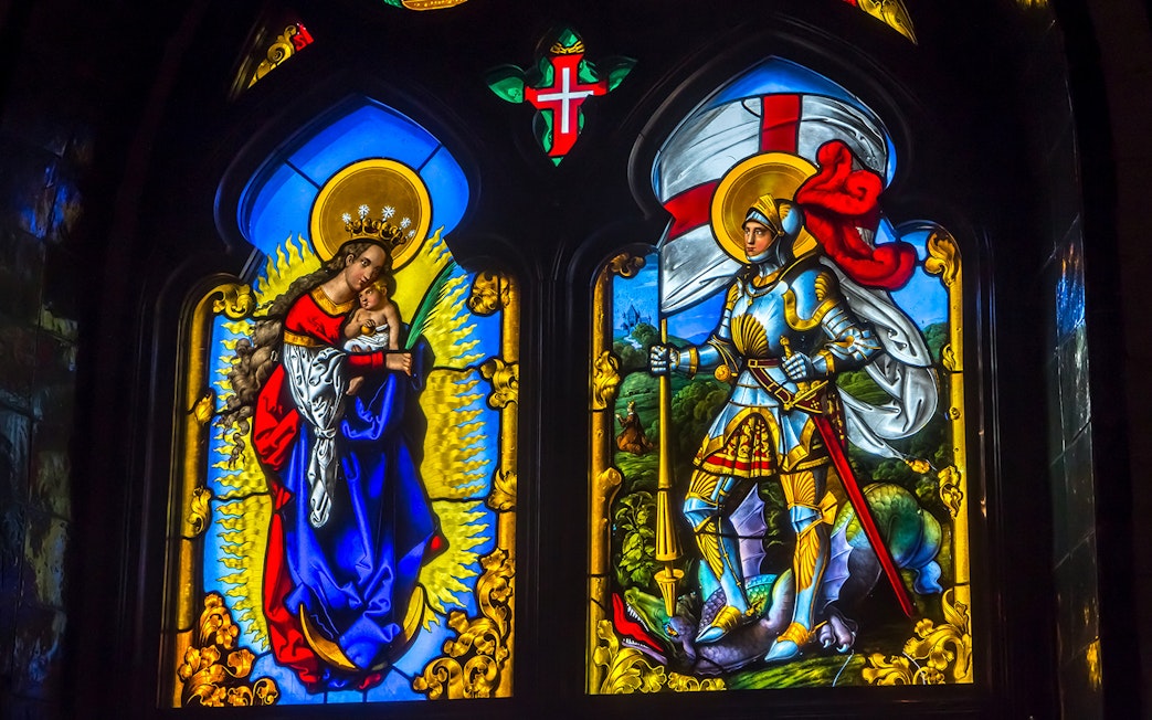 Stained glass window at National Palace of Pena depicting religious figures and knight.