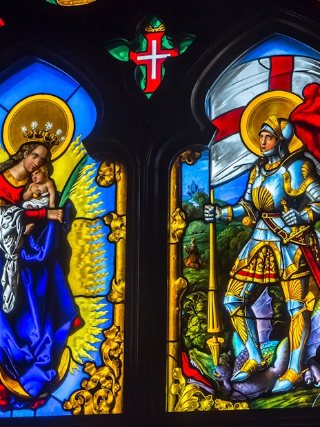 Stained glass window at National Palace of Pena depicting religious figures and knight.