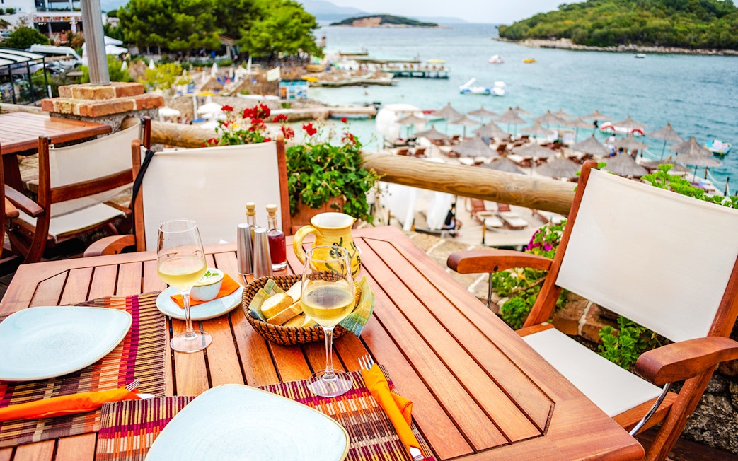 Lunch setting with wine and bread overlooking Ksamil Islands beach during day trip from Tirana.