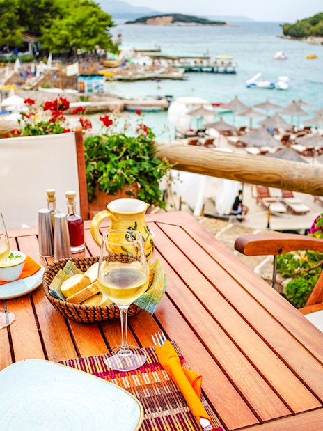 Lunch setting with wine and bread overlooking Ksamil Islands beach during day trip from Tirana.