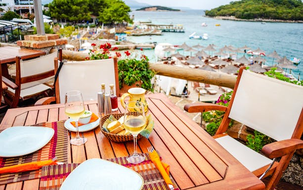 Lunch setting with wine and bread overlooking Ksamil Islands beach during day trip from Tirana.