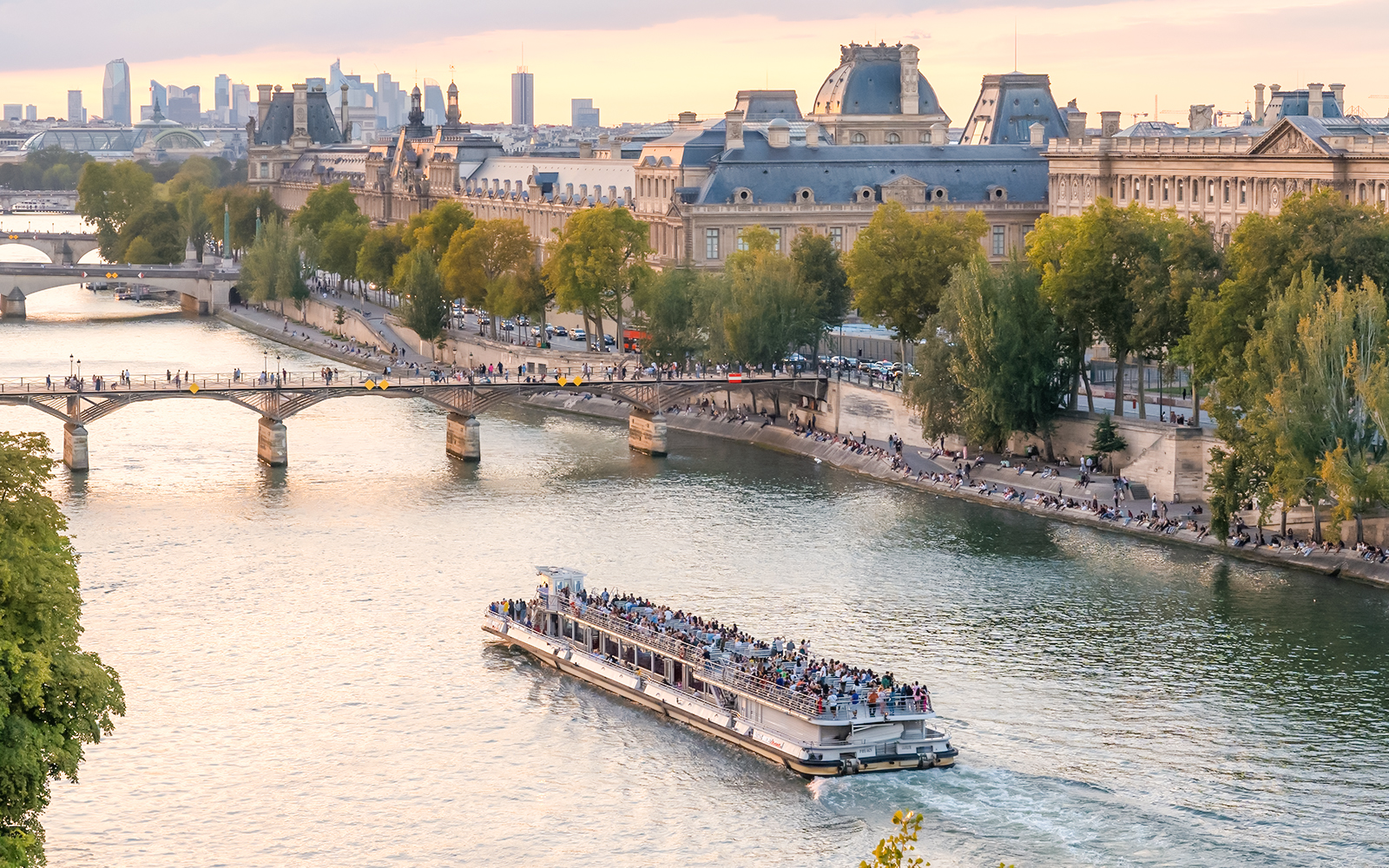 Seine River cruise boat passing by the Louvre Museum in Paris.