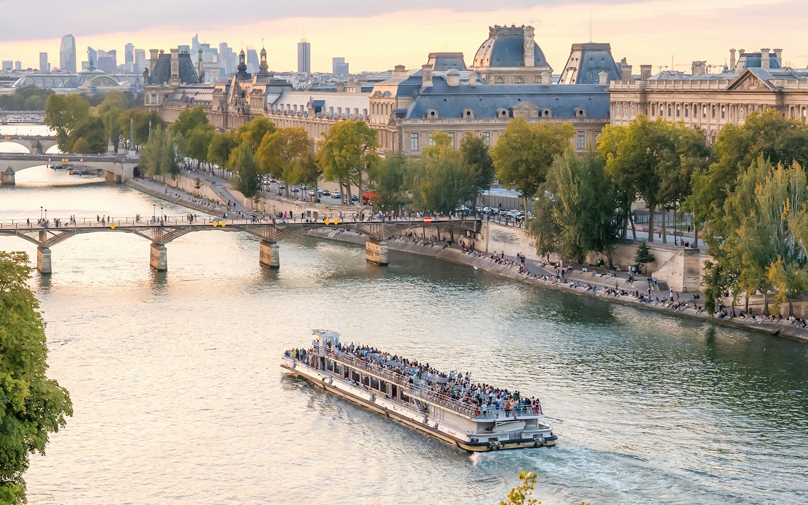 Seine River cruise boat passing by the Louvre Museum in Paris.