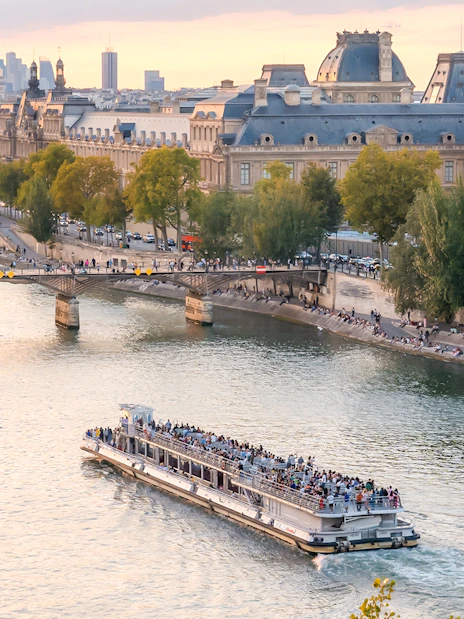 Seine River cruise boat passing by the Louvre Museum in Paris.