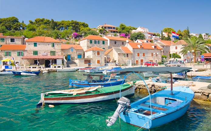 Boats docked in the harbor of Maslinica, Solta Island, Croatia, with stone houses in the background.