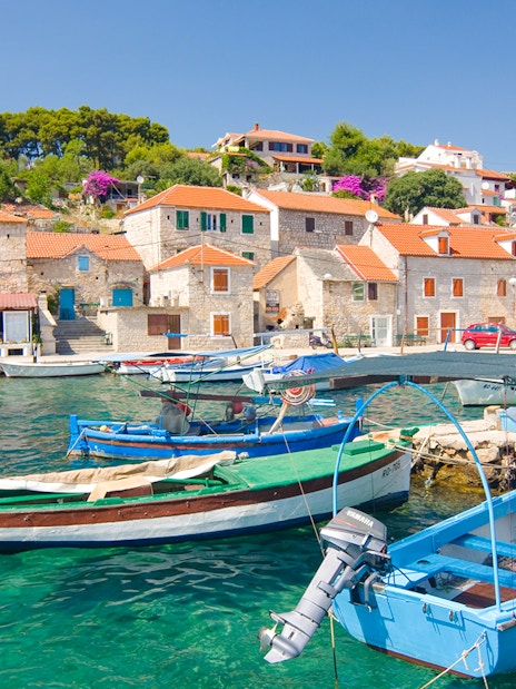 Boats docked in the harbor of Maslinica, Solta Island, Croatia, with stone houses in the background.