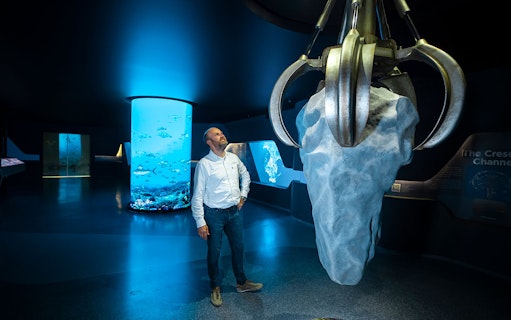 Man observing large claw sculpture at The View At The Palm exhibit.