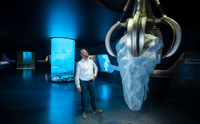 Man observing large claw sculpture at The View At The Palm exhibit.