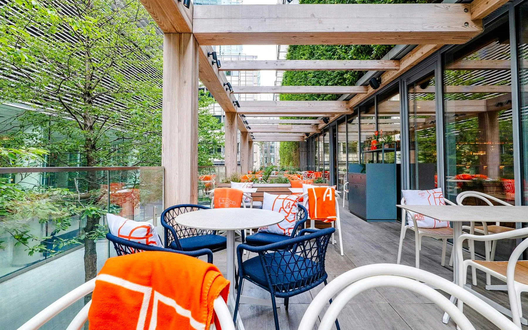 Outdoor seating area at The Larch, Skygarden London, with tables and chairs under a wooden pergola.