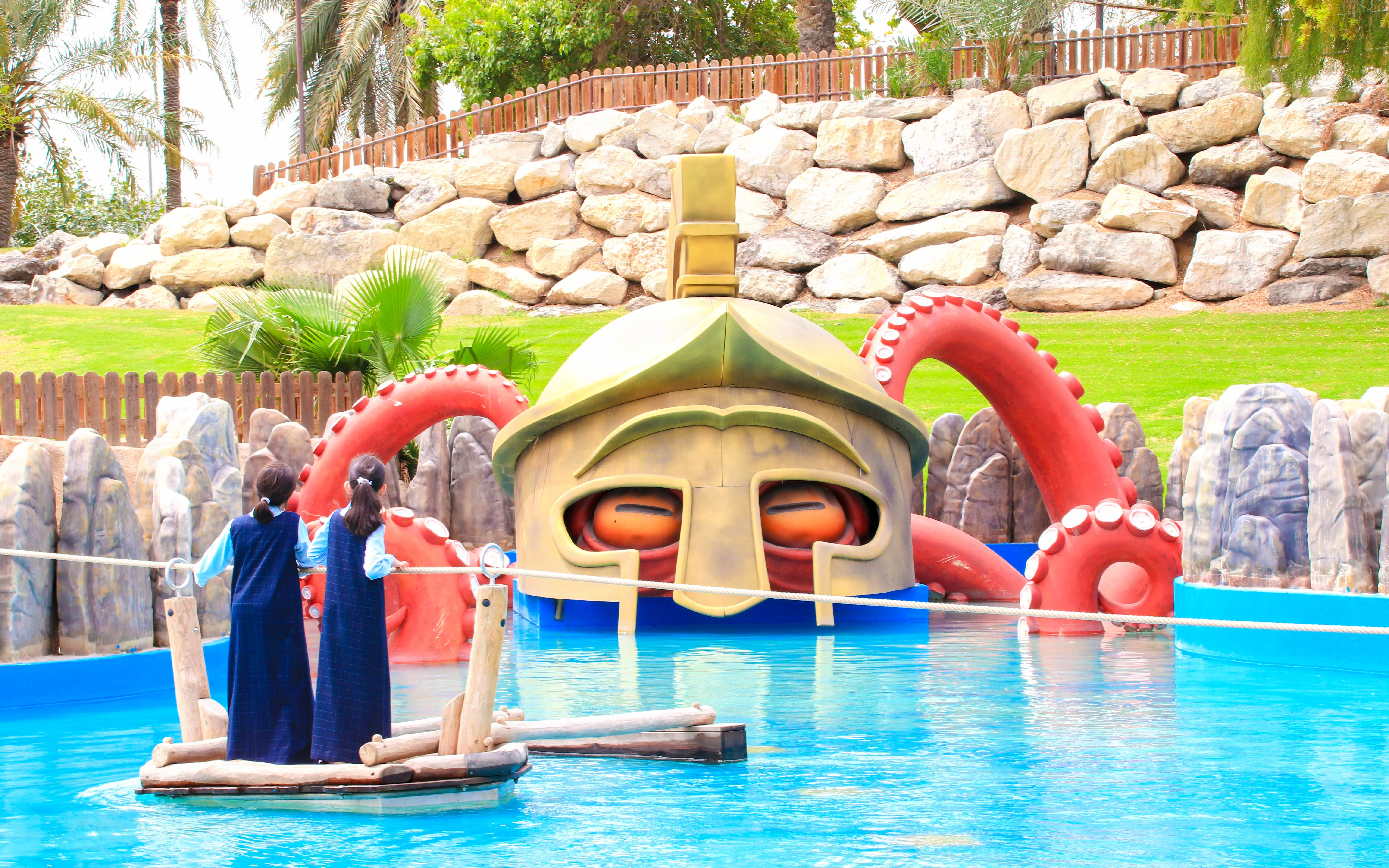 Children on a raft near a giant helmet and octopus tentacles at Al Montazah Parks.
