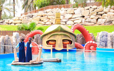 Children on a raft near a giant helmet and octopus tentacles at Al Montazah Parks.