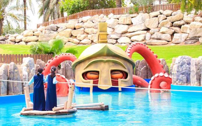 Children on a raft near a giant helmet and octopus tentacles at Al Montazah Parks.