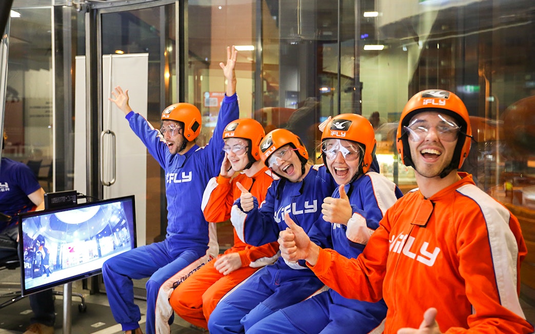 Group of people in flight suits and helmets excited for iFLY Indoor Skydiving Experience.