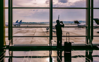 Traveler photographing planes at Zanzibar airport window.